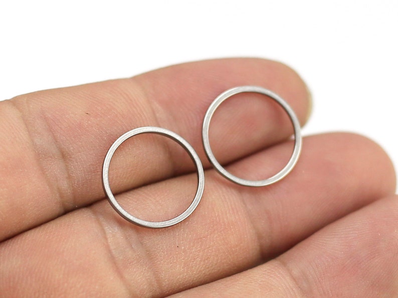 May include: A pair of silver hoop earrings. The earrings are simple and minimalist, with a smooth, polished finish.