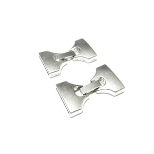 May include: Two silver-toned metal buckles with a symmetrical, flared shape. Each buckle consists of two wide, trapezoidal ends connected by a central rectangular hinge, featuring a smooth, reflective finish and a clean, industrial design.