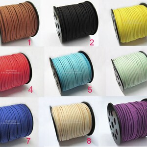 Op de afbeelding: Negen spoelen suède koord in verschillende kleuren, waaronder bruin, zwart, geel, rood, turquoise, lichtgroen, blauw, beige en paars. Elke spoel is genummerd van 1 tot 9.