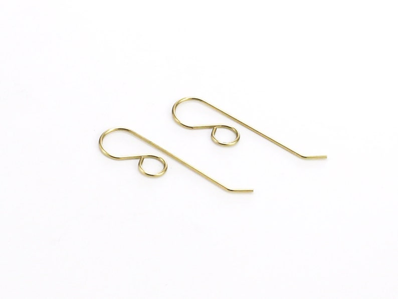 May include: Two gold-toned earring hooks, each with a small loop at the top and a longer, slightly curved wire extending from the loop.