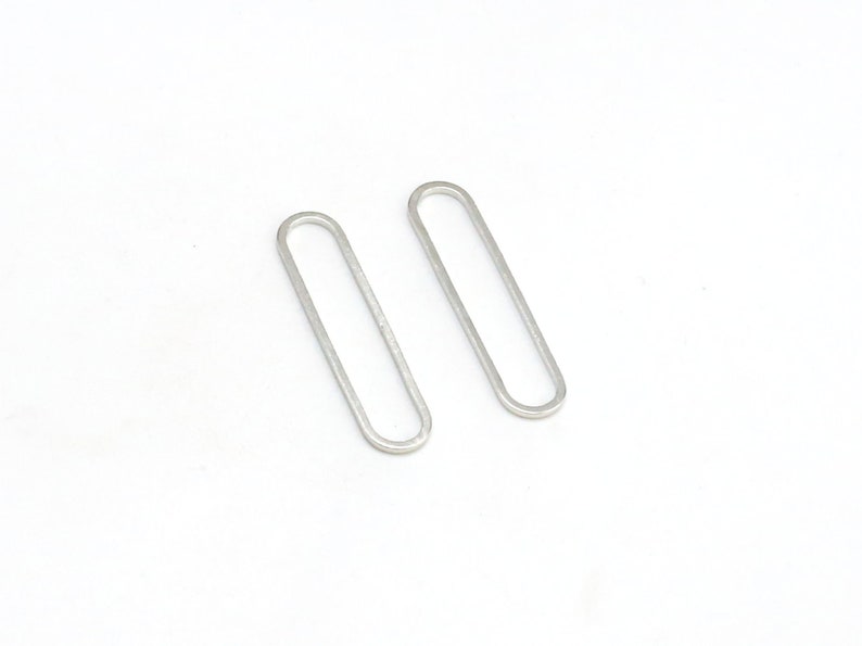 May include: A pair of silver oval-shaped earrings. The earrings are simple and minimalist in design.