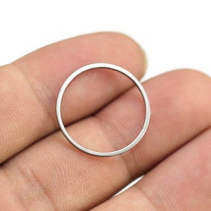 May include: A silver-colored metal ring, shown held in a hand.