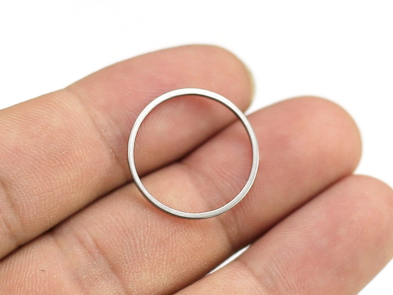 May include: A silver-colored metal ring, shown held in a hand.