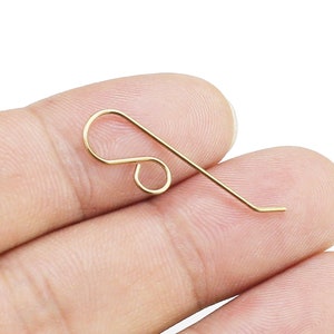 May include: A gold-colored metal earring hook with a loop at the top and a straight wire extending from the loop.