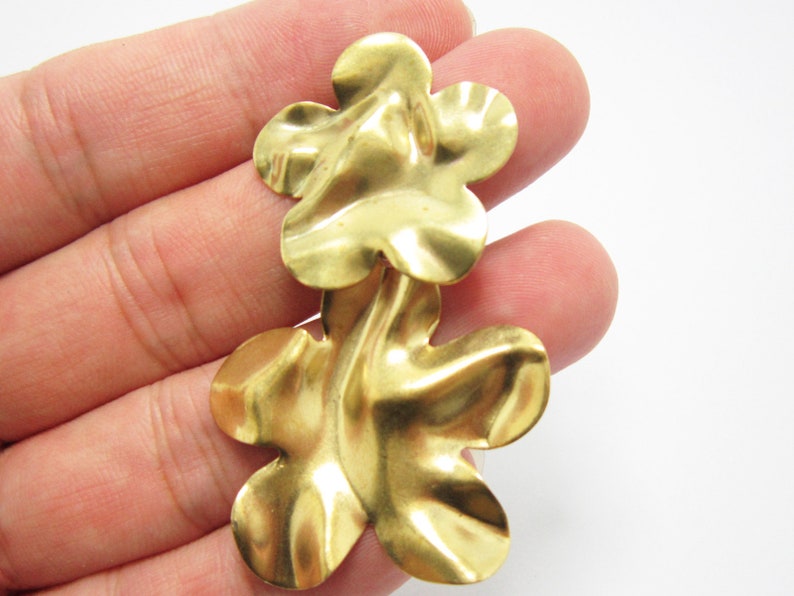 K&ouml;nnte beinhalten: Ein Paar goldfarbene Ohrringe in Blumenform. Die Ohrringe bestehen aus zwei &uuml;bereinanderliegenden Blumen, jede mit f&uuml;nf Bl&uuml;tenbl&auml;ttern.