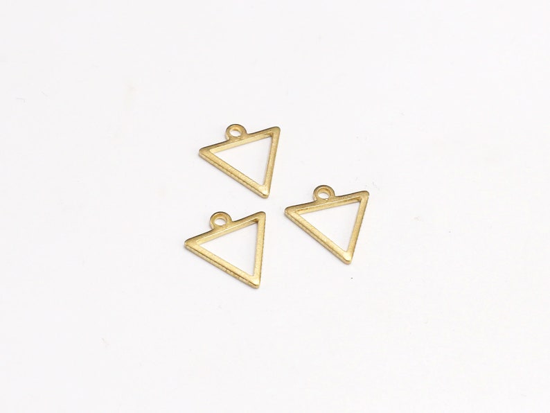 May include: Three gold triangle shaped metal charms with a loop at the top for attaching to jewelry or other crafts.