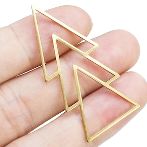 May include: A gold metal geometric shape in the form of two overlapping triangles. The shape is made of thin wire and has a simple, modern design.