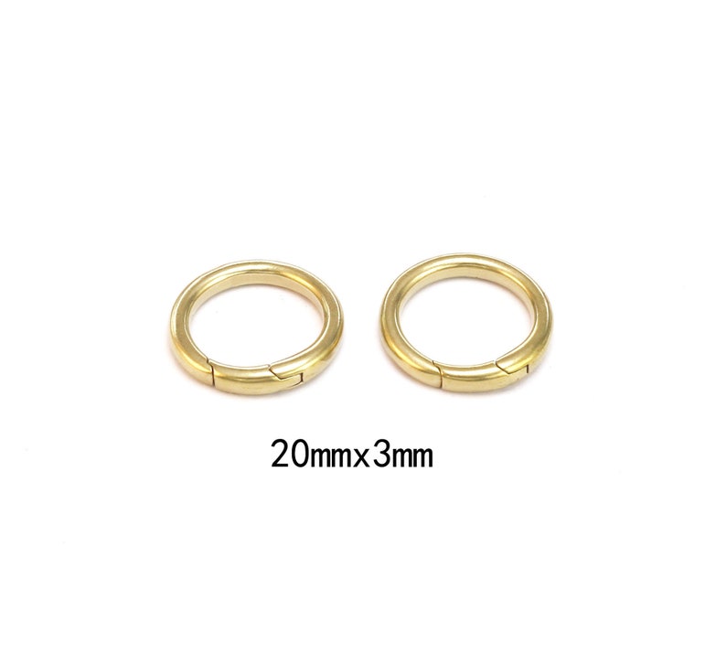 Pode incluir: Dois an&eacute;is de metal dourado com fecho articulado. Os an&eacute;is t&ecirc;m 20 mm de di&acirc;metro e 3 mm de espessura. Fundo branco.