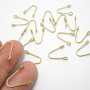 May include: A group of 15 gold-toned metal loop closures. The loops are about 1 inch long and have a small opening at the top.