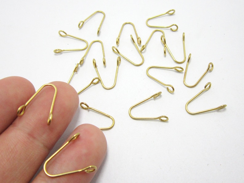 May include: A group of 15 gold-toned metal loop closures. The loops are about 1 inch long and have a small opening at the top.