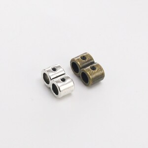 May include: Two metal bead caps, one silver and one bronze, with two holes each. The caps are designed to be used as end caps for jewelry making.