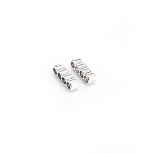 May include: Two silver metal connector bars with five holes each. The bars are arranged in a parallel fashion.