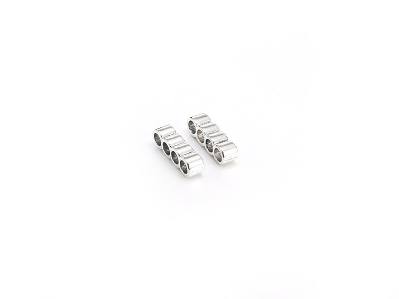 May include: Two silver metal connector bars with five holes each. The bars are arranged in a parallel fashion.