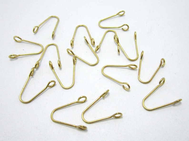 May include: A group of 14 gold-toned metal hooks with a loop at each end. The hooks are arranged in a random pattern on a white surface.