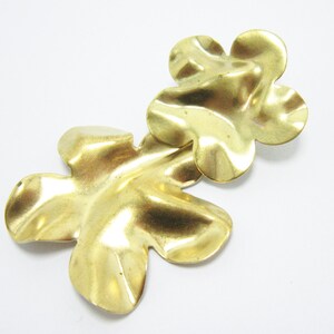 K&ouml;nnte beinhalten: Zwei goldfarbene, metallene Bl&uuml;ten-Anh&auml;nger mit strukturierter Oberfl&auml;che.