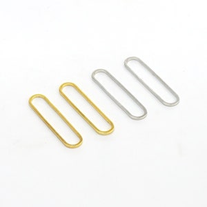 May include: Four oval-shaped metal rings, two gold and two silver, arranged in a row on a white background.