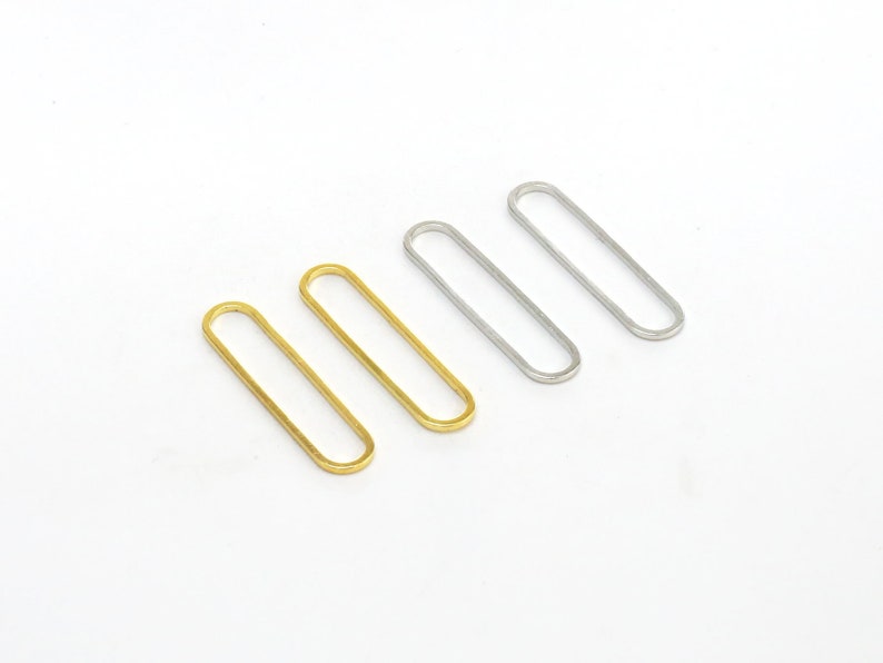 May include: Four oval-shaped metal rings, two gold and two silver, arranged in a row on a white background.