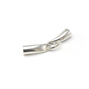 May include: Silver-toned metal end cap for jewelry making. The end cap has a tube shape with a small loop on one end and a curved end on the other.