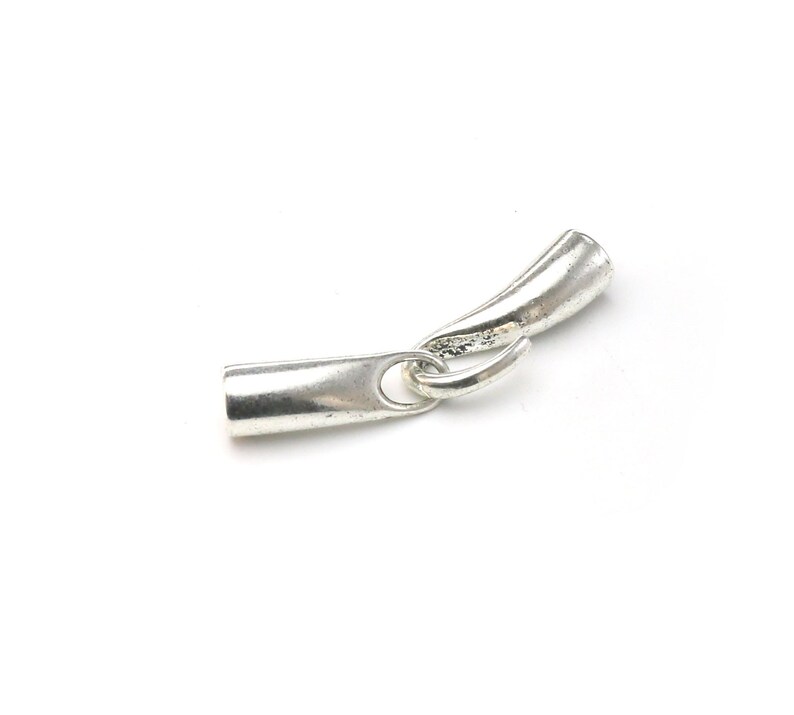 May include: Silver-toned metal end cap for jewelry making. The end cap has a tube shape with a small loop on one end and a curved end on the other.