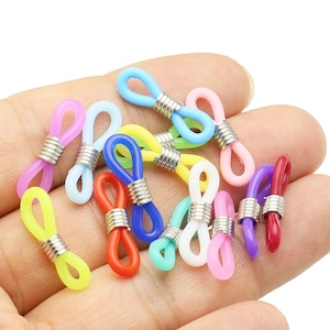 以下が含まれることがあります： 金属製のアクセントが付いたカラフルなプラスチック製の眼鏡チェーンホルダーの詰め合わせ。ホルダーは、青、緑、黄、ピンク、赤など、さまざまな色があります。