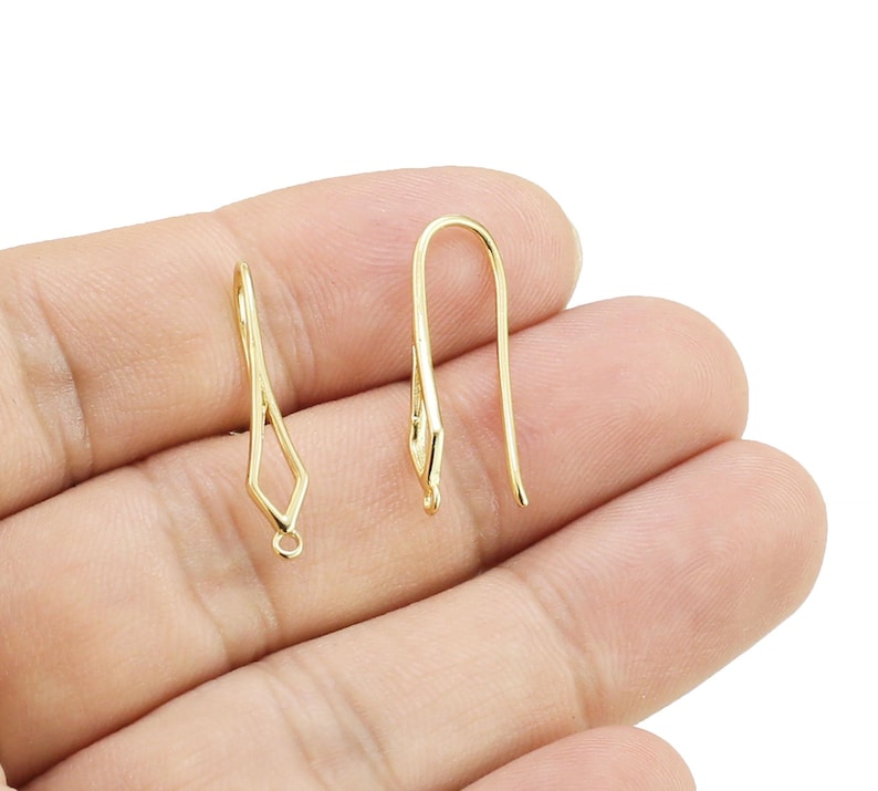 May include: Three gold earring hooks, two are simple and one has a diamond shape at the top.