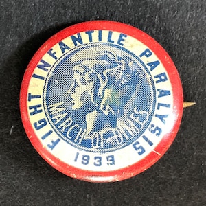 May include: A vintage button with a red border and a white and blue center. The button reads "FIGHT INFANTILE PARALYSIS" and "MARCH OF DIMES" with the year "1939" at the bottom. The image features a profile of a person.