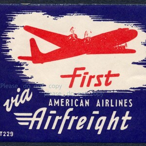 Pode incluir: Anúncio vintage da American Airlines Airfreight. O design apresenta uma silhueta de avião vermelha sobre um fundo branco, emoldurada em azul escuro. A palavra "First" está em destaque em vermelho, com "via" e "Airfreight" em branco. O texto "T229" está em baixo.