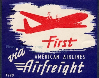 Può includere: Annuncio pubblicitario vintage per American Airlines Airfreight. Il design presenta una silhouette di aereo rossa su sfondo bianco, incorniciata in blu scuro. La parola "First" è in rosso, con "via" e "Airfreight" in bianco. Il testo "T229" è in basso.