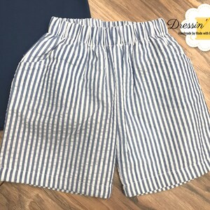 Pu&ograve; includere: Shorts a righe blu e bianche con elastico in vita. I pantaloncini hanno una tasca su ogni lato.