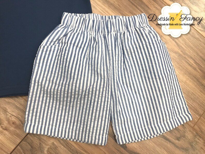 Pu&ograve; includere: Shorts a righe blu e bianche con elastico in vita. I pantaloncini hanno una tasca su ogni lato.
