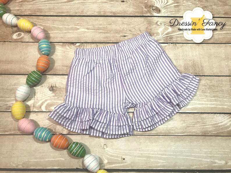 Puede incluir: Shorts de rayas blancas y moradas con un dobladillo con volantes. Los shorts est&aacute;n hechos de una tela ligera y tienen una cintura el&aacute;stica c&oacute;moda.