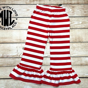 Puede incluir: Pantalones de rayas rojas y blancas con un volante en la parte inferior. Los pantalones tienen una cintura el&aacute;stica.
