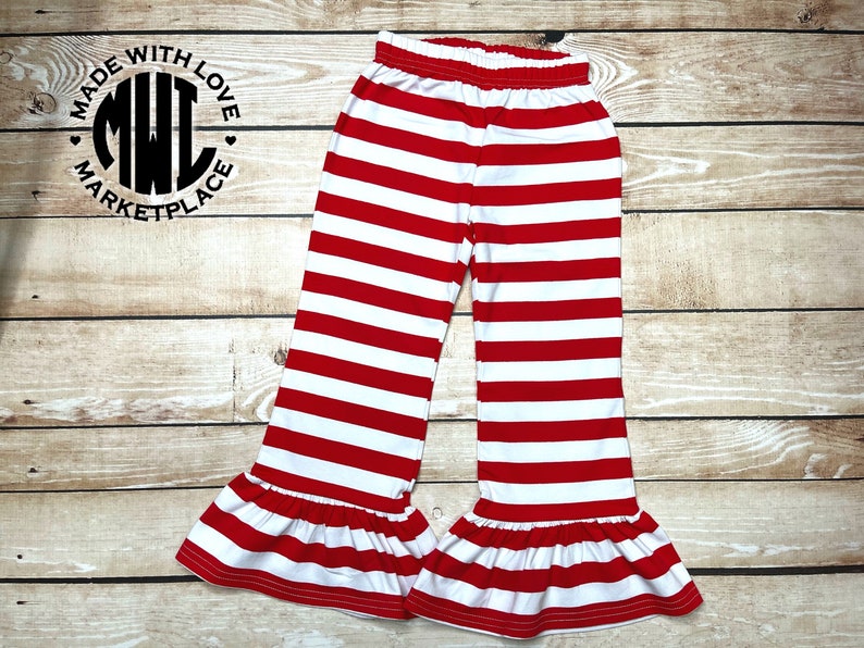 Puede incluir: Pantalones de rayas rojas y blancas con un volante en la parte inferior. Los pantalones tienen una cintura el&aacute;stica.