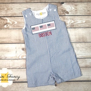May include: A blue and white striped baby onesie with a red, white, and blue embroidered American flag design and the name "Easton" embroidered below.