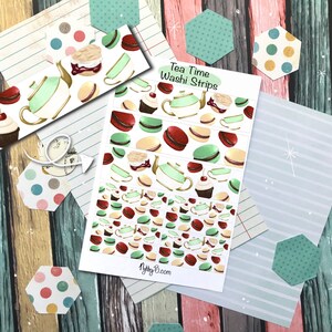 May include: Washi tape strips with a tea time theme. The strips feature illustrations of teapots, macarons, and cupcakes in green, brown, and white. The text "Tea Time Washi Strips" is visible on the product.