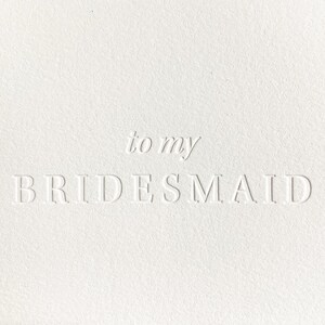 K&ouml;nnte beinhalten: Eine wei&szlig;e Karte mit gepr&auml;gtem Text, der &bdquo;to my BRIDESMAID&ldquo; lautet. Die Karte hat eine strukturierte Oberfl&auml;che und der Text ist in einer einfachen, eleganten Schriftart gehalten. Die &Auml;sthetik ist sauber und minimalistisch.