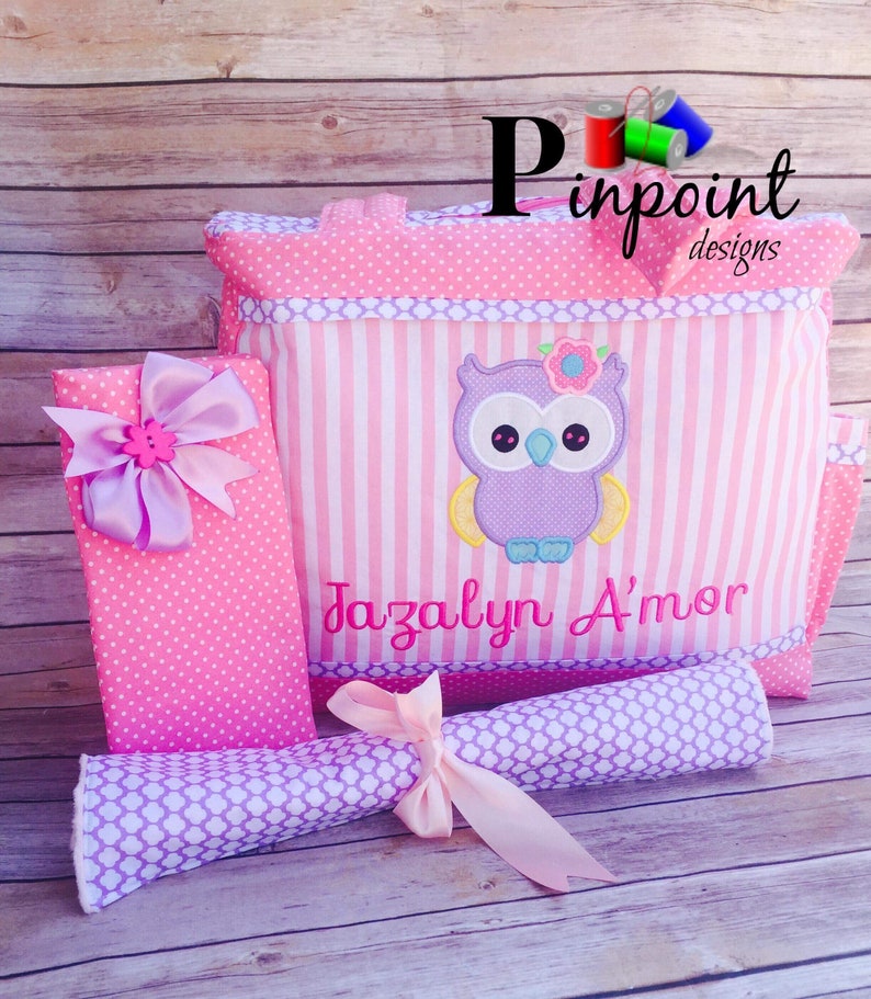 Puede incluir: Bolso cambiador de tema b&uacute;ho rosa y morado con una colchoneta cambiadora a juego y una peque&ntilde;a bolsa de regalo rosa y blanca con lunares. El bolso tiene una tela a rayas rosa y blanca con un b&uacute;ho morado bordado en &eacute;l. El bolso est&aacute; personalizado con el nombre "Jazalyn D'mor".
