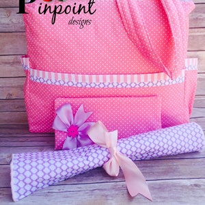 Puede incluir: Bolso tote de lunares rosa con ribete a rayas morado y blanco y una bolsa m&aacute;s peque&ntilde;a a juego. El bolso tote tiene un asa de tela rosa y la bolsa tiene una cinta rosa atada alrededor. El bolso tote tiene el texto "Pinpoint Designs" en la parte delantera.