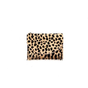 May include: A small rectangular wallet featuring a textured animal print pattern with black spots on a tan background. The wallet has a curved flap closure secured with a single centered metal stud, showcasing a soft, fur-like material texture.