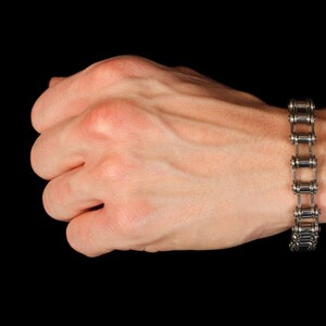 May include: A silver chain bracelet made from linked bicycle chain links.