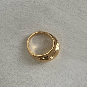 Op de afbeelding: Een gouden ring met een afgeronde, gladde en licht gewelfde bovenkant.