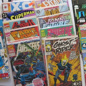 May include: A collection of vintage comic books featuring colorful covers with titles like "Cable," "Superman," and "Ghost Rider." The comics are stacked, showcasing various characters and vibrant artwork.