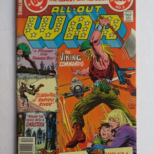 May include: A comic book cover featuring a muscular man in a military uniform, holding a large axe and standing in front of a burning plane. The cover is titled "All-Out War" and features the text "The Viking Commando".