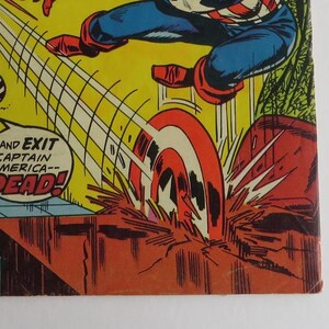 Puede incluir: Una p&aacute;gina de c&oacute;mic con Captain America, un superh&eacute;roe, con un traje rojo, blanco y azul. Est&aacute; volando por el aire con su escudo, que gira y deja un rastro de luz. El texto en la p&aacute;gina dice "--and EXIT CAPTAIN AMERICA-- DEAD!"