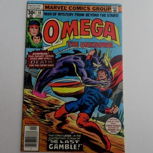 May include: A comic book cover featuring a superhero in a blue and red costume fighting a purple demon. The comic book is titled "Omega the Unknown" and the cover text reads "Man of Mystery from Beyond the Stars!"