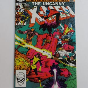 May include: A comic book cover featuring the X-Men. The cover is green, red, yellow, and blue. The title "The Uncanny X-Men" is in large, bold letters. The characters Wolverine, Storm, Cyclops, and Colossus are featured on the cover.