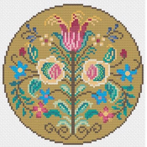 May include: A circular cross-stitch pattern featuring a stylised floral design with a central flower in shades of pink and red, surrounded by smaller flowers in blue, yellow, and pink. The background is a warm brown colour.