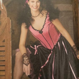 May include: A pink and black costume with a corset-style top and a layered skirt. The top has black trim and a V-neck. The skirt is black with pink ribbons. The costume is accessorized with lace wrist cuffs and a choker.