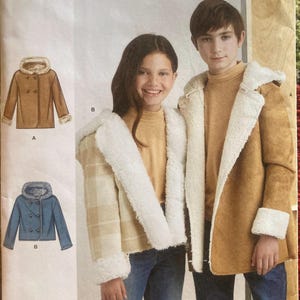 May include: Simplicity sewing pattern S9832 featuring two children wearing coats with faux fur trim. The pattern includes illustrations of a brown coat and a blue coat. The size range is U.S. 7-14.
