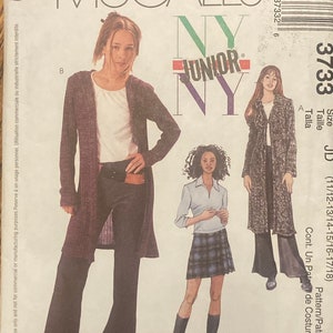 May include: A sewing pattern for a junior size cardigan and skirt. The pattern is from McCall's and is for sizes 11/12 to 17/18. The pattern includes instructions for making a long-sleeved cardigan with a hood and a plaid skirt.